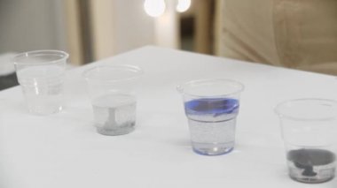 Plastik bardaklardaki renklerle epoksi reçinesini karıştıran bir kadın.