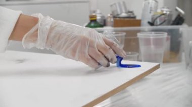 Açık yüzeye mavi renkli epoksi reçine döken bir kadın.