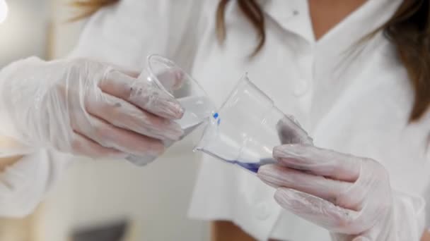 Eine Frau mischt buntes Epoxidharz in einer Tasse — Stockvideo