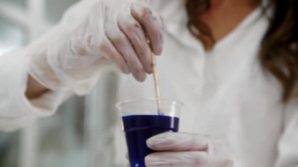 Una mujer que mezcla resina epoxi azul profundo en la taza de plástico — Vídeo de stock