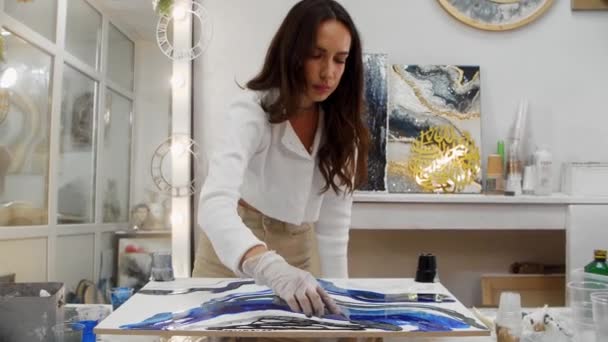 Young woman drawing design on a surface using dark blue epoxy resin and spatula — Stock Video