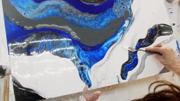 Рисование картины белой и голубой эпоксидной смолой с использованием лопатки — стоковое видео