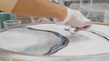 Epoksi tasarım - beyaz epoksi reçineyi bir spatula kullanarak yuvarlak resmin üzerine sürmek