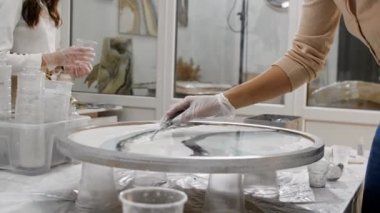 Resim stüdyosundaki bir spatulayı kullanarak yuvarlak resme beyaz epoksi reçinesi sürmek.