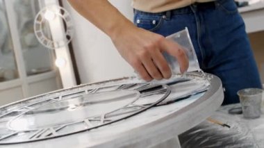 Genç bir kadın, yuvarlak epoksi reçine resminin kenarlarına açık doku parçaları ekliyor.