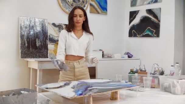 Una mujer utiliza un quemador para una pintura hecha de resina epoxi — Vídeo de stock