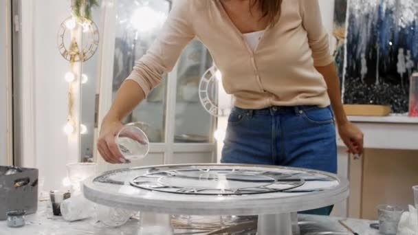 Mujer joven añadiendo piezas de textura clara en los bordes de una pintura epoxi redonda — Vídeo de stock