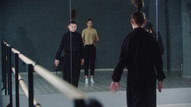 Küçük kız ikizler eş zamanlı olarak stüdyoda dans ediyorlar ve koçları onlara göz kulak oluyor.