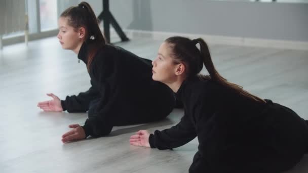 Маленькі дівчата близнюки синхронно практикують свої танці в студії — стокове відео