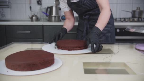 Pasticceria: una donna taglia un pan di Spagna al cioccolato in due parti — Video Stock