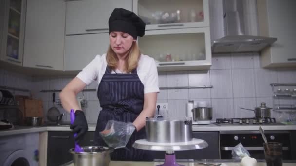 Confeitaria - uma mulher coloca creme de chocolate no saco de pastelaria — Vídeo de Stock