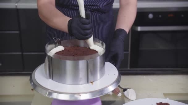 Suikergoed - een vrouw giet vanille crème op de chocolade bisquit in de vorm — Stockvideo