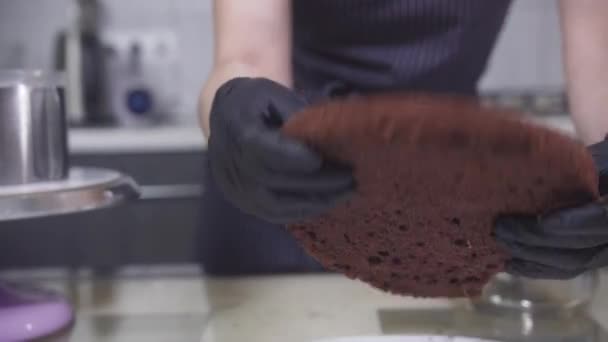 Suikergoed - een vrouw zet de laatste chocolade bisquit op de basis van de taart — Stockvideo