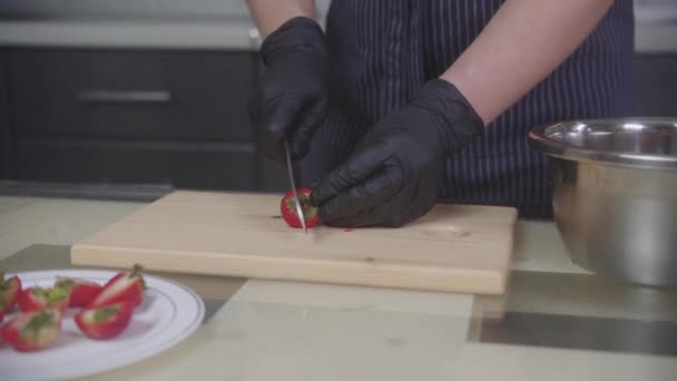 Confeitaria - chef de pastelaria corta morangos ao meio — Vídeo de Stock