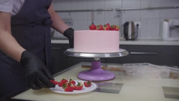 Wyroby cukiernicze - cukiernik zdobiący różowe ciasto świeżymi truskawkami — Wideo stockowe