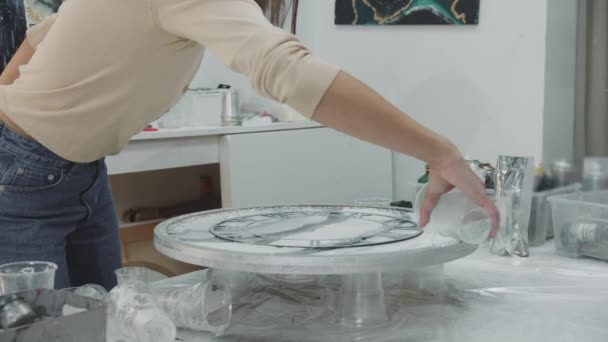 Mujer addsclear piezas de textura en los bordes de una pintura redonda de resina epoxi — Vídeo de stock