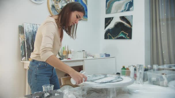 Giovane donna finisce la pittura resina epossidica in una forma di orologio e versando pezzi chiari intorno alla circonferenza per la testurizzazione — Video Stock