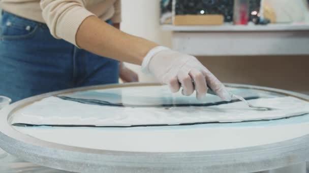 Mujer joven aplanando la superficie de un objeto de arte de resina epoxi redonda usando una espátula — Vídeo de stock