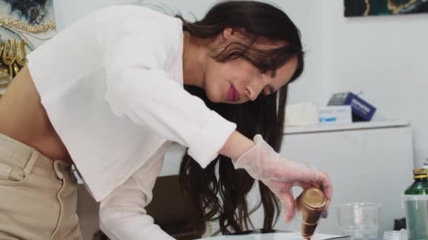 Junge Frau gießt goldenes Glitzerepoxid auf das Gemälde — Stockvideo