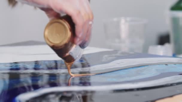 Jeune femme versant l'époxy pailleté doré sur la peinture de la tasse — Video
