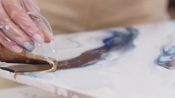 Jovem mulher derramando para baixo o dourado brilhante epóxi na pintura a partir do copo de plástico — Vídeo de Stock