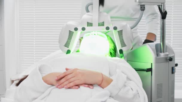 Elektrikli yüz temizleme - genç bir kadının yüzünde parlayan yeşil bir cihaz - kozmetoloji — Stok video
