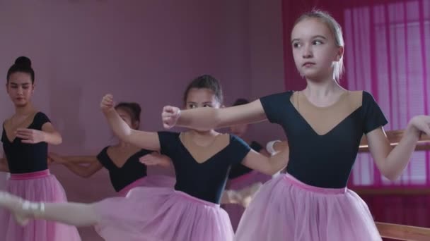 Trening baletowy - pięć dziewcząt w pięknych sukienkach trenujących i rozciągających się przy trybunach w studio — Wideo stockowe
