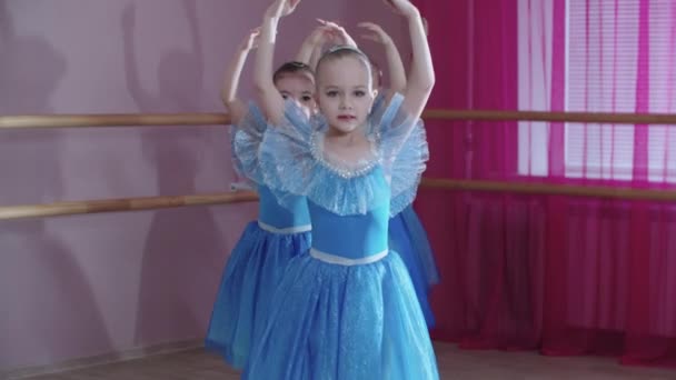 Ballet training - vier ballerina meisjes in blauwe jurken lopen vooruit in een rij en gaan rond — Stockvideo
