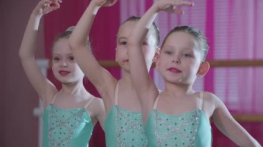 Bale eğitimi. Mavi elbiseli üç balerin kız bale pozisyonu alıyorlar.