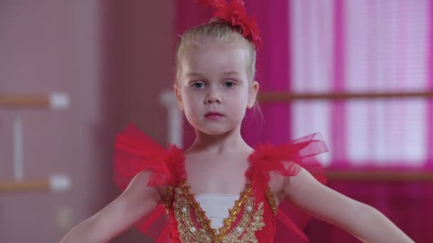 Entrenamiento de ballet - una niña seria en vestido rojo de pie en posición de ballet — Vídeos de Stock