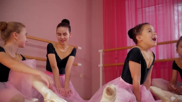 Öt gyönyörű ruhás balerina lány ül a földön és beszélgetnek egymással. — Stock videók