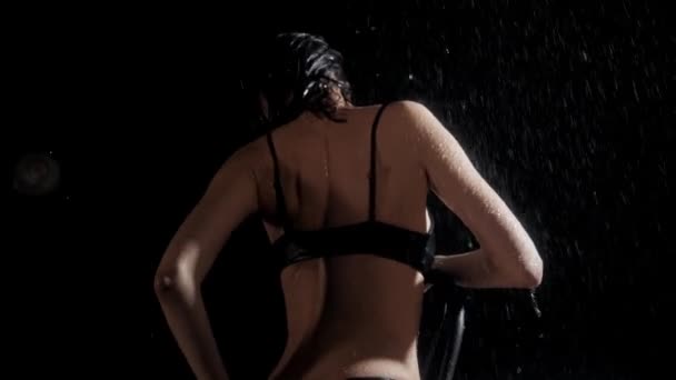 Islak vücutlu genç bir kadın yağmurda sandalyeye oturur ve tenine dokunur. — Stok video