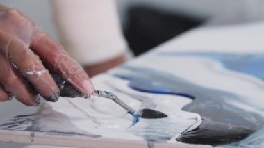 Beyaz epoksi reçineyi spatulayla boyuyor.