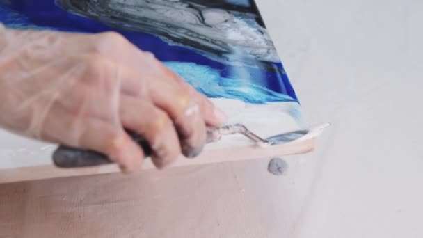 Мажет белую эпоксидную смолу на картине шпателем на абстрактной картине — стоковое видео