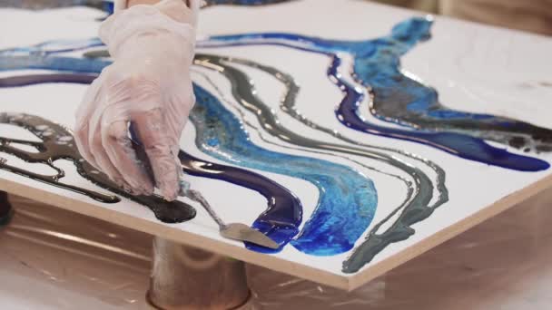 Smearing dark blue epoxy resin on the canvas using a spatula — Stock Video