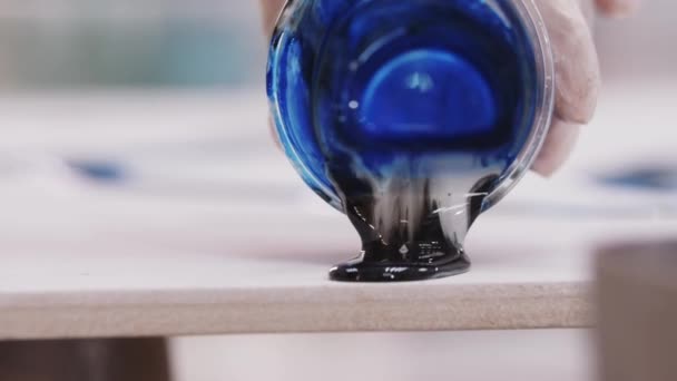 Kunstenaar giet mix van diepblauwe en zwarte epoxyhars op doek — Stockvideo