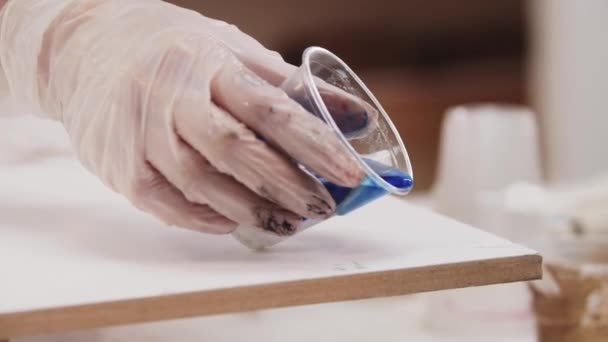 Künstler gießt Mischung aus blauen Farben von Epoxidharz auf Leinwand — Stockvideo