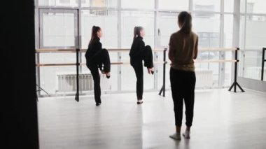 Koreografi. Stüdyoda iki kız esniyor ve öğretmen onları izliyor.