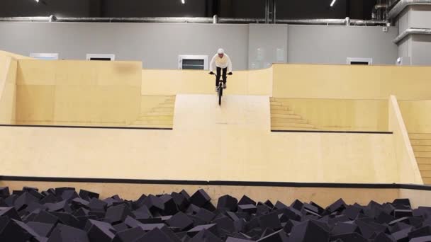 BMX esportes - jovem montando e fazendo um flip, em seguida, cai na piscina cheia de esponjas — Vídeo de Stock