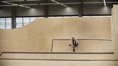 BMX spor - genç adam rampalarda bisiklet sürüyor ve numaralar yapıyor.
