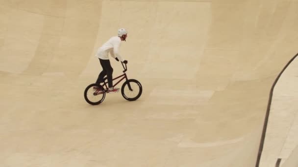 Jovem cavalgando nas rampas de sua bicicleta esportiva no campo de treinamento — Vídeo de Stock