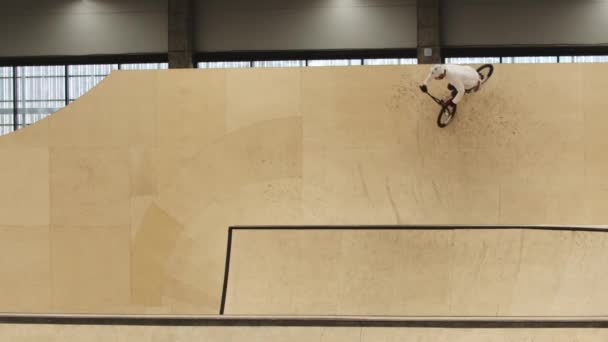 Joven montando en las rampas de madera contrachapada en su bicicleta deportiva — Vídeos de Stock