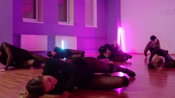 Groupe de femmes en vêtements noirs dansant sur le sol en studio avec éclairage violet — Video