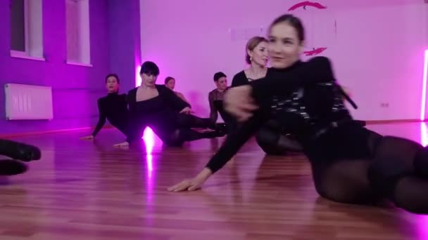 Grupo de mujeres sexy en ropa negra bailando en el suelo en el estudio con iluminación púrpura — Vídeos de Stock