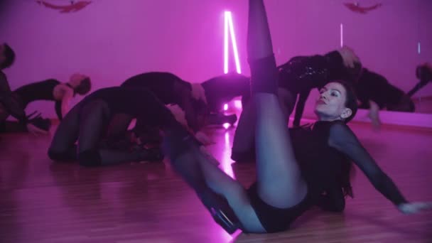 Groep van sexy slanke vrouwen in zwart kleding dansen op de vloer in paarse verlichting — Stockvideo