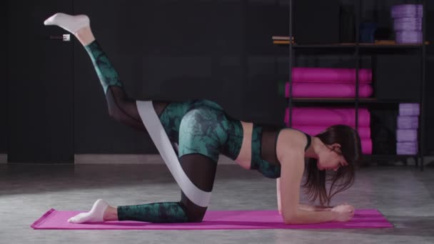 Mladá sportovní žena pomocí elastické pásku na bocích při protahování a cvičení — Stock video