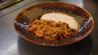 Şef tabak soslu makarna servis ediyor.