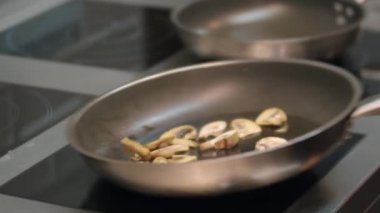 Şef etkili bir şekilde mantarları kızartma tavasına atar.