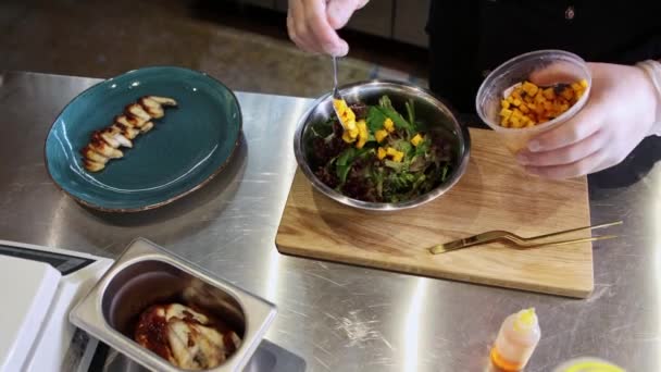 Chef serverar fiskbitar med sallad med mangoskivor och sås — Stockvideo