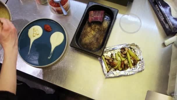 Le chef sert le plat dans une assiette - les ingrédients sont sur la table sur les côtés — Video